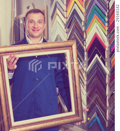 Man worker holding picture frame details on counter Man worker holding picture frame details on counter 29168182