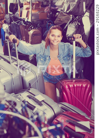 portrait of teenage girl picking new big plastic luggage bag with wheels in shop 29168229