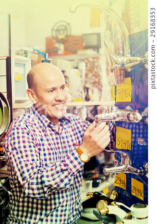 Mature positive man selecting heating water tap in store 29168353