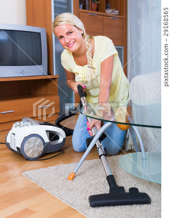 Blonde girl hoovering in living room . 29168565
