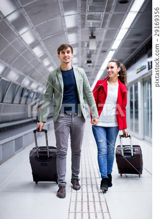 Portrait of couple with wheeled trollers at subway platform 29169356