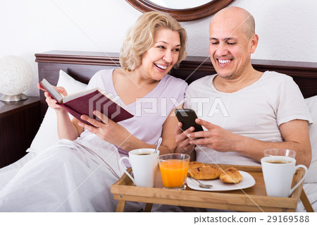 man showing girlfriend something on book during breakfast 29169588