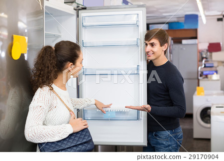 family couple choosing new refrigerator in hypermarket family couple choosing new refrigerator in hypermarket 29170904