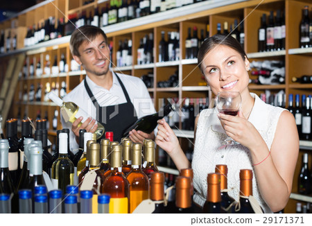 portrait of glad female customer tasting wine before purchasing 29171371