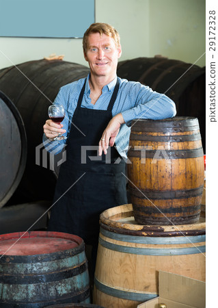 friendly seller male wearing apron suggesting to try glass of wine 29172328