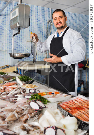 Seller behind scales and fish counter showing fish Seller behind scales and fish counter showing fish 29172937