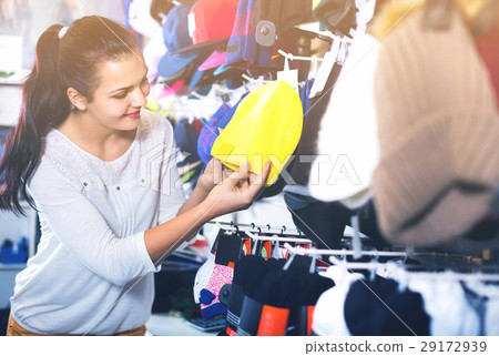 Female customer examining knit caps in sports store 29172939
