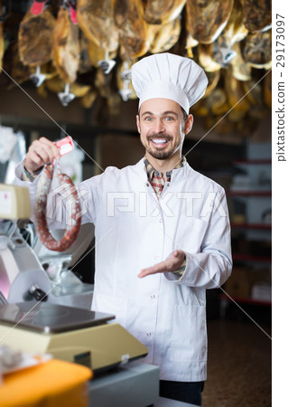 Smiling male seller weighing on scales sausage 29173097