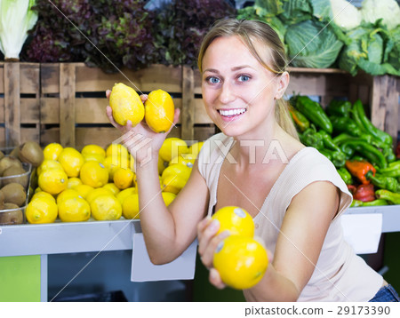 attractive woman holding lemons in hands in fruit store 29173390