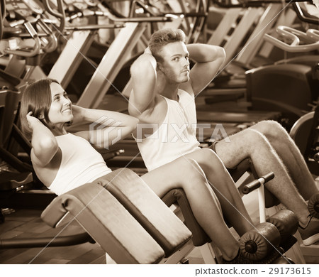 Well trained glad young man and woman training abdominal muscles in gym Well trained glad young man and woman training abdominal muscles in gym 29173615