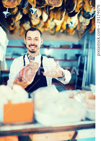 Male shop assistant demonstrating piece of meat in butcher’s shop Male shop assistant demonstrating piece of meat in butcher’s shop 29174076