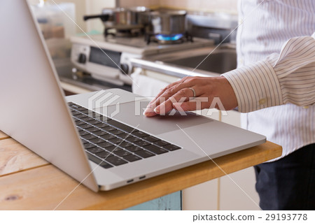 A man using a personal computer in the kitchen 29193778