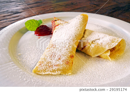 Rolled crepes with red jam on wooden background Rolled crepes with red jam on wooden background 29195174