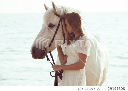 Girl in white dress with horse on the beach Girl in white dress with horse on the beach 29195808
