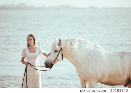 Girl in white dress with horse on the beach Girl in white dress with horse on the beach 29195840