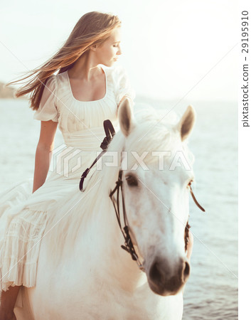 Girl in white dress with horse on the beach 29195910