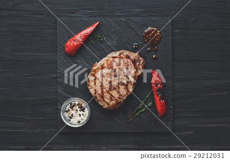 Grilled beef steak on dark wooden table background Grilled beef steak on dark wooden table background 29212031