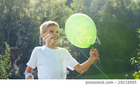 Handsome smiling boy holds green balloon having Handsome smiling boy holds green balloon having 29218985