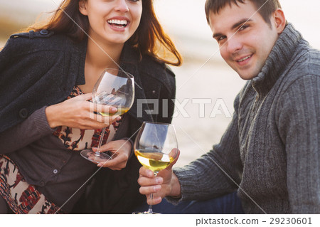 Couple enjoying picnic with white wine on beach Couple enjoying picnic with white wine on beach 29230601