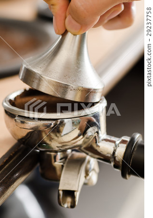 Barista pressing ground coffee into portafilter Barista pressing ground coffee into portafilter 29237758