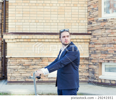 A handsome young businessman rolling his bicycle A handsome young businessman rolling his bicycle 29241931