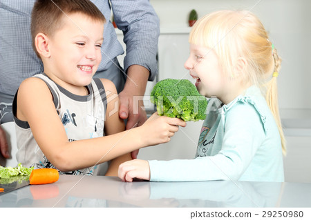 Smiling cute daughter and son biting a broccoli. Smiling cute daughter and son biting a broccoli. 29250980