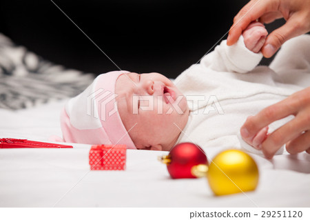male hands touching cute crying baby near gifts  29251120
