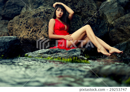 lady in red dress sitting on the stone 29253747