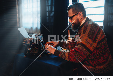 Bearded writer in glasses typing on a typewriter Bearded writer in glasses typing on a typewriter 29254756