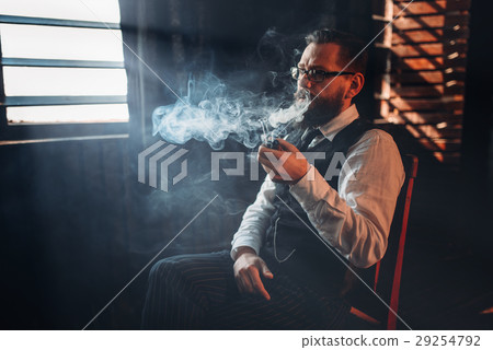 Portrait of man sitting on chair and smoking pipe Portrait of man sitting on chair and smoking pipe 29254792
