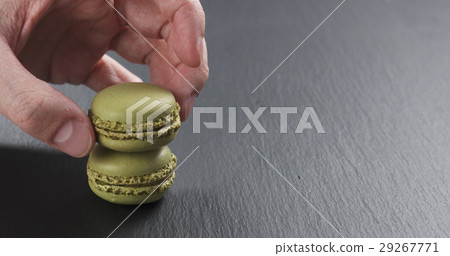 man hand stacking pistachio macarons on slate 29267771