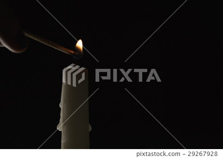 lighting a tall candle with match over black lighting a tall candle with match over black 29267928
