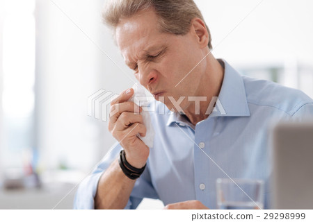 Disturbed male person while wiping his nose 29298999