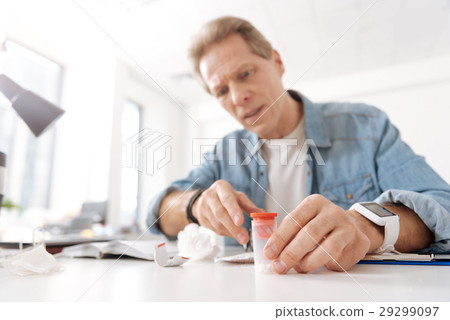 Attentive male person staring on box with pills Attentive male person staring on box with pills 29299097