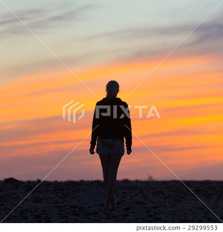 Woman on rocky beach watching sunset. 29299553