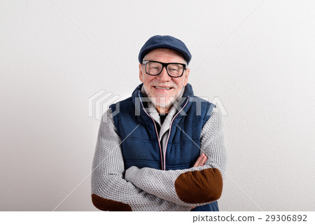Senior man in sweater, vest jacket and cap, studio 29306892