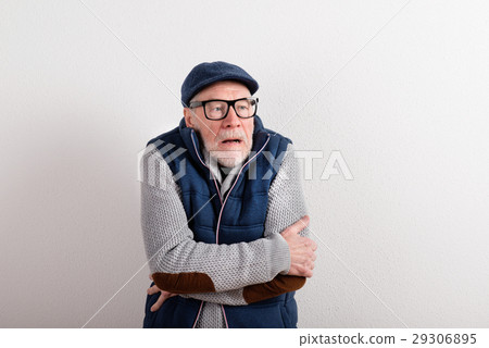 Senior man in sweater, vest jacket and cap, studio 29306895