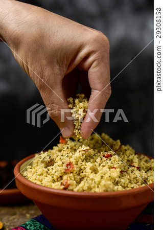 young man eating tabbouleh with his hand 29308158