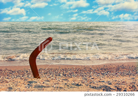 Boomerang on sandy coastline against sea wave 29310266
