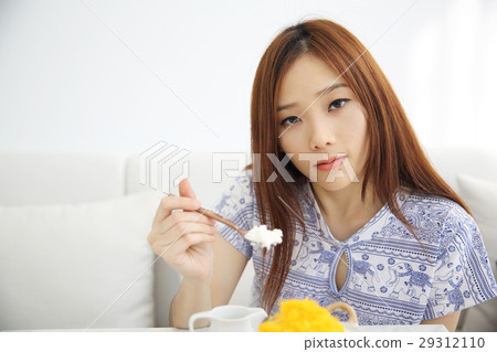 Asian young woman eating Shaved ice with milk and coconut Asian young woman eating Shaved ice with milk and coconut 29312110