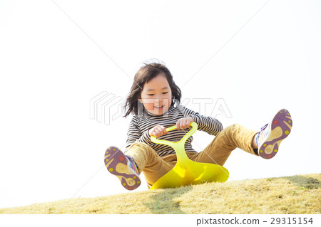 A girl playing with a grass sled 29315154