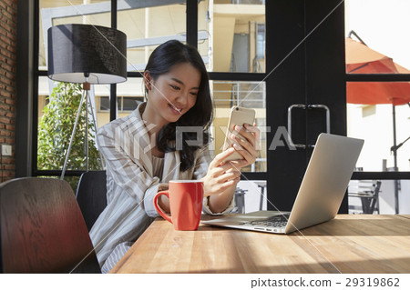 The woman using smartphone and smiling happily The woman using smartphone and smiling happily 29319862