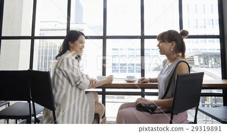 Two pretty women is talking to each other in a nice and modern office Two pretty women is talking to each other in a nice and modern office 29319891