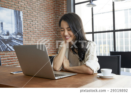 The woman is looking at the laptop screen and smiling 29319892