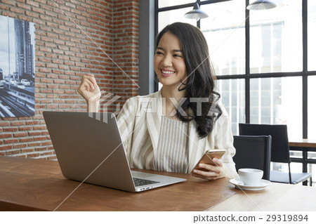 The young lady is smiling at something and holding her smarphone in hand 29319894