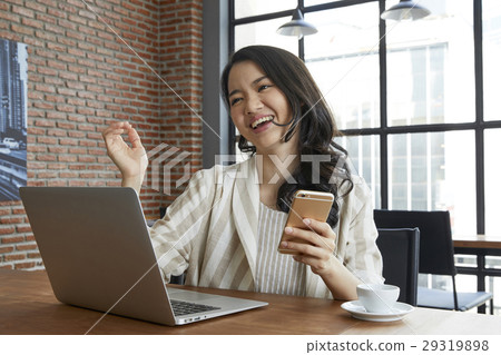 The woman is holding her smartphone and smiling happly in the morning The woman is holding her smartphone and smiling happly in the morning 29319898