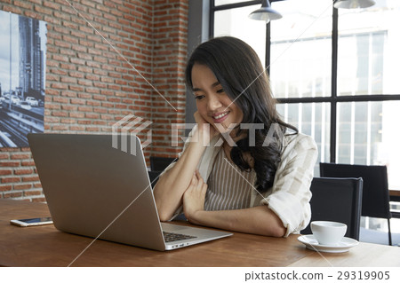 Young lady is working with her laptop and seems satisfied with it. Young lady is working with her laptop and seems satisfied with it. 29319905