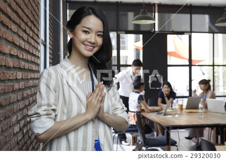The beautiful woman smiling while colleagues discussing at the back. The beautiful woman smiling while colleagues discussing at the back. 29320030