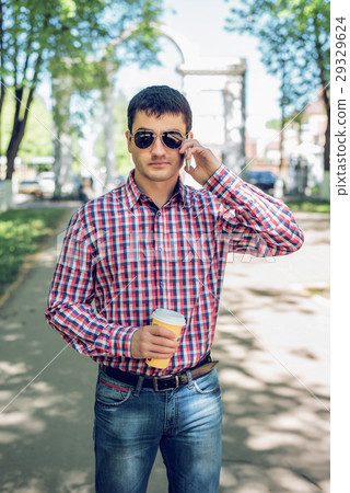 man in  shirt and jeans  glasses, talking on t 29329624