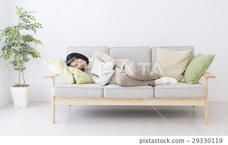 A woman who fell asleep on a sofa holding a tablet A woman who fell asleep on a sofa holding a tablet 29330119